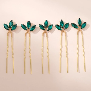 Set of five gold hair pins with emerald green rhinestone leaf motifs in a flat lay view