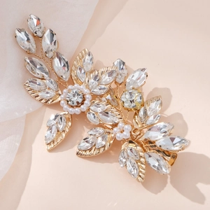 Detailed close-up of golden leaf bridal hair clip with crystals and pearls on soft silk