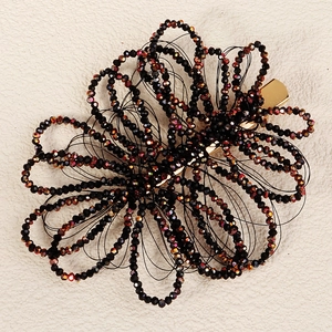 Detail of handcrafted black crystal flower hair clip with iridescent beads and gold base