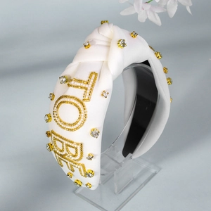 Detail eines weißen Satin-Haarreifs mit goldener LOVE-Perlenstickerei und Strass