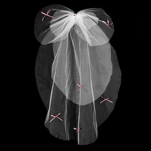 Détail d'un voile de mariée blanc orné de nœuds en soie rose et d'une pierre