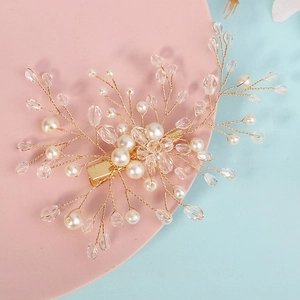 Dettaglio di fermaglio per capelli da sposa fatto a mano con filo d'oro, perle e cristalli