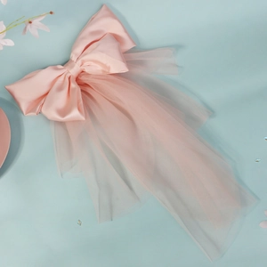 Detail view of pink satin bow hair accessory with multi-layered bridal tulle veil