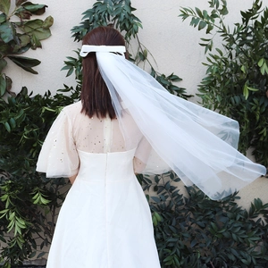 Détail d'un voile de mariée blanc élégant avec nœud en satin et textures de tulle multicouche