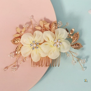 Détail d'un peigne de mariée fait main avec fleurs en tissu ivoire et perles de cristal