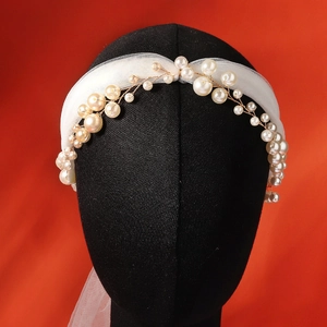 Détail d'un bandeau en perles fait main avec tulle blanc et fil doré sur un mannequin