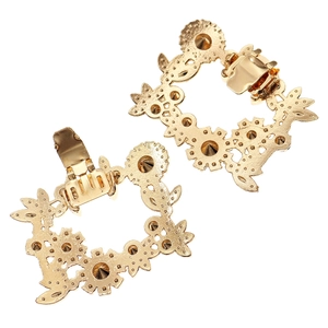 Nahaufnahme goldener Schuhclips mit floralem Durchbruchmuster und Federverschluss