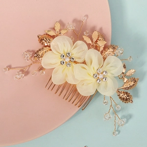 Détail d'un peigne de mariée avec fleurs en tissu blanc et feuilles dorées élégantes