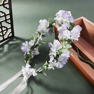 Close-up of lavender and white floral headband with silk ribbons and green leaves