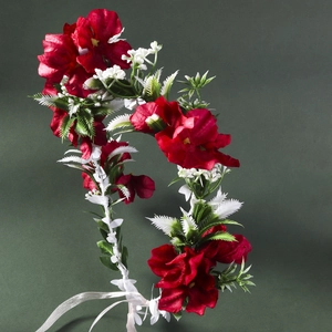 Detailed macro view of vibrant red fabric roses and green foliage on bridal floral headband