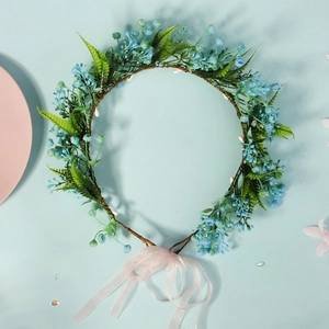 Detail of floral bridal headband with blue berries, green leaves and pink ribbon bow