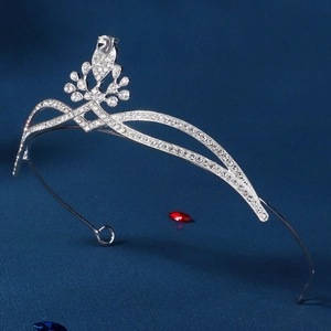 Close-up of elegant silver tiara with sparkling zircons on deep blue background