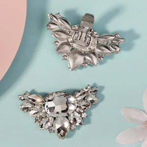 Detail von silbernen Schuhclips mit funkelnden Kristallen und metallener Krokodilklemme