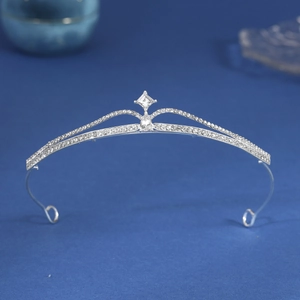 Detailed view of silver bridal crown with intricate zircon rhinestones on blue background