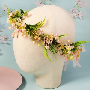 Detail of pink handmade floral bridal crown with green leaves and white lace ribbon
