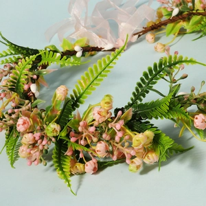 Macro detail of bridal flower crown with pink blossoms and delicate green fern leaves