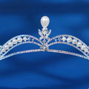 Elegant silver bridal crown with white pearls and sparkling rhinestones on blue silk