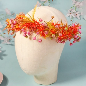 Detail of floral crown with orange star flowers and pink berries on foam model