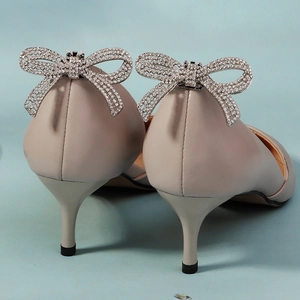 Detailansicht der glitzernden Strass-Schleifen an eleganten beigefarbenen Stiletto-Schuhen