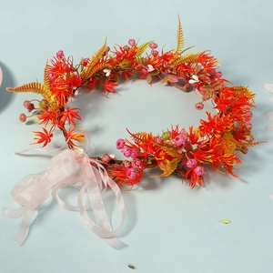 Detailed close-up of orange and red floral wreath headband with delicate pink silk ribbons
