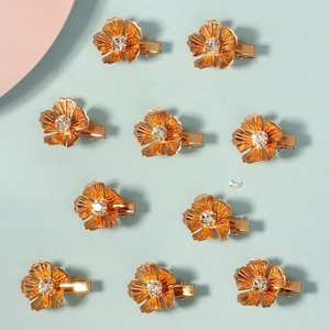 Detailed set of ten gold flower hair clips with sparkling crystal centers on blue background