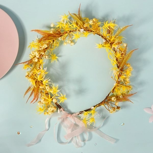Detailed close-up of yellow floral wreath crown with orange ferns and pink ribbon tie