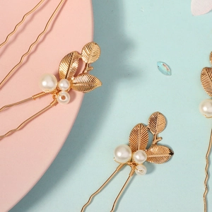 Détail d'épingles à cheveux feuilles dorées avec perles blanches sur fond élégant