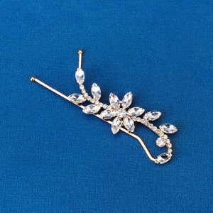 Detail of floral gold hairpin with marquise rhinestones on textured blue fabric