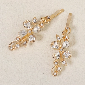 Detailed macro view of two gold floral rhinestone hair clips with sparkling crystals