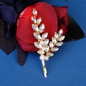 Detailed close-up of a gold leaf hair clip with shiny rhinestones and white pearls