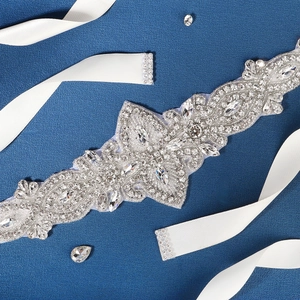 Détail d'une ceinture de mariée avec cristaux marquise et ruban en satin blanc