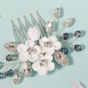 Detailed macro view of white clay flowers and crystals on a bridal hair comb accessory