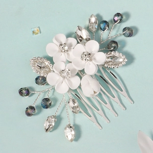 Close-up of white clay flowers and crystal beads on a silver wedding hair comb