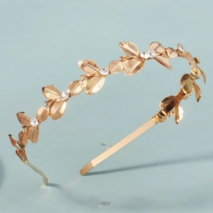 Dettaglio del cerchietto con foglie dorate, strass trasparenti e trame venate