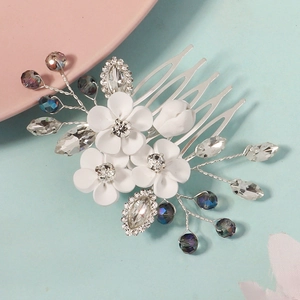 Detailed macro view of white clay flowers and crystals on a silver bridal hair comb