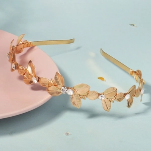 Dettaglio macro del cerchietto con foglie dorate e strass su un piatto in ceramica