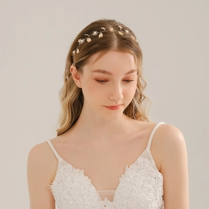 Détail du bandeau de mariée avec de délicates feuilles en métal doré et des perles blanches