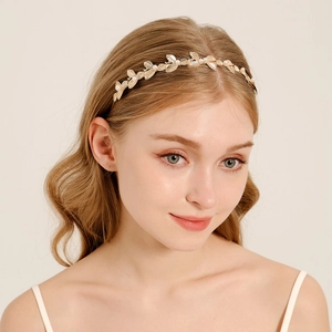 Elegante cerchietto per capelli con foglie dorate e perle bianche su modella