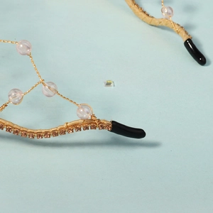 Détail du serre-tête fait main en fil doré avec perles roses et strass marron