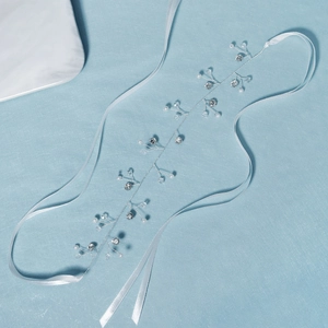 Détail de vigne à cheveux mariée argentée avec perles blanches, cristaux et rubans
