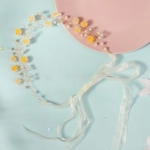 Détails de fleurs en acrylique jaune et perles sur le bandeau de mariée avec rubans