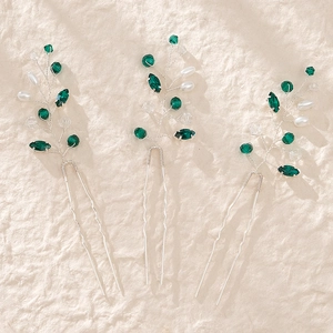 Detailed set of silver hair pins with emerald crystals and white pearls for styling