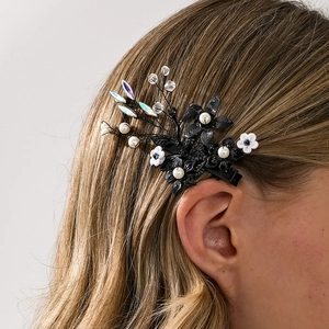 Detail von handgemachter schwarzer Blumen-Haarklammer mit Perlen auf hellbraunem Haar