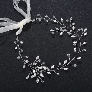 Détail d'une vigne de cheveux de mariée avec fil d'argent, cristaux, perles et ruban blanc