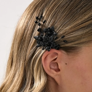 Details von handgefertigtem schwarzen Blumen-Haarclip mit Perlen auf braunem Haar
