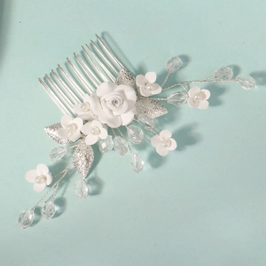 Detail of bridal hair comb with white roses, crystals and silver leaves on blue background