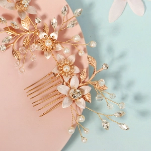 Détail d'un peigne à cheveux pour mariée avec fleurs dorées, perles blanches et cristaux