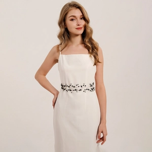 Close-up of handmade bridal belt with black crystals on a white slim-fit party dress