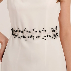 Detailed close-up of handmade black crystal and beaded embellishment on a white bridal belt