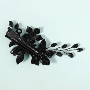 Detailaufnahme einer schwarzen Haarspange aus Metall mit Blumen und facettierten Perlen
